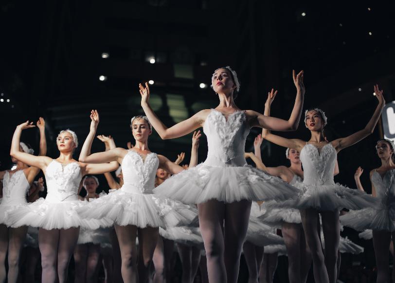 group of ballerinas dancing while raising both hands
